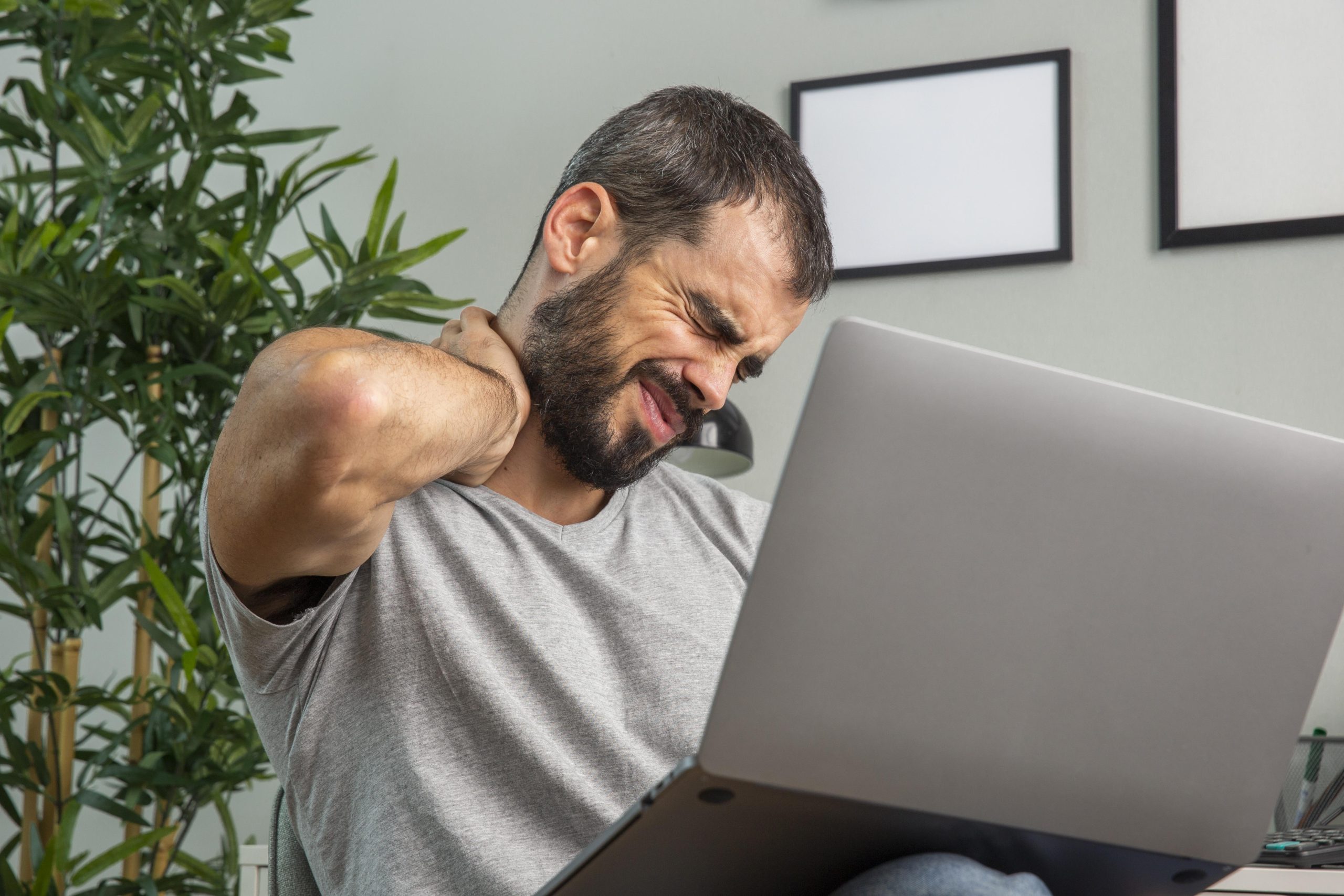 Omuz Ağrısı Yaşıyorsanız Hangi Tedavi Yöntemleri Sizi Rahatlatır? 3 man experiencing neck pain while working from home laptop scaled